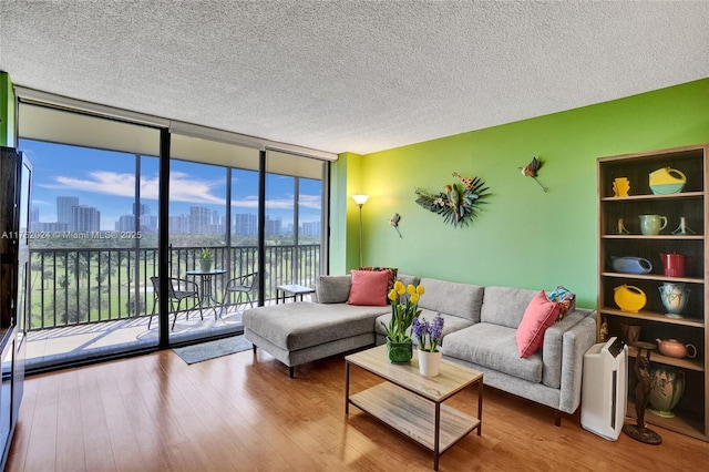 living room with a textured ceiling, a view of city, a wall of windows, and wood finished floors