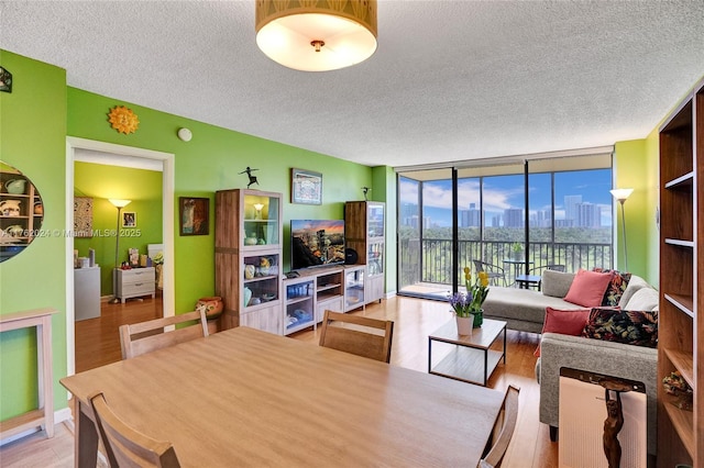 dining room with floor to ceiling windows, light wood-style floors, and a textured ceiling