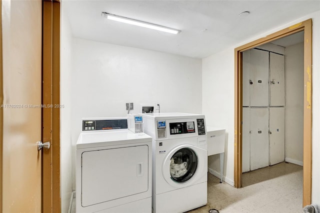 community laundry room with washing machine and dryer, baseboards, and light floors