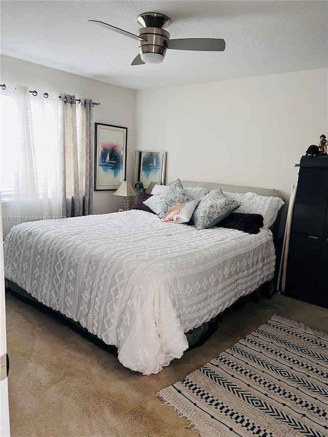 bedroom featuring a textured ceiling, a ceiling fan, and carpet floors