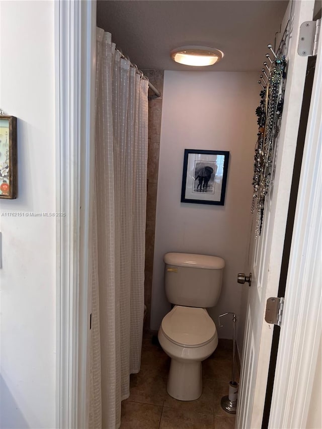 bathroom with curtained shower, baseboards, toilet, and tile patterned flooring