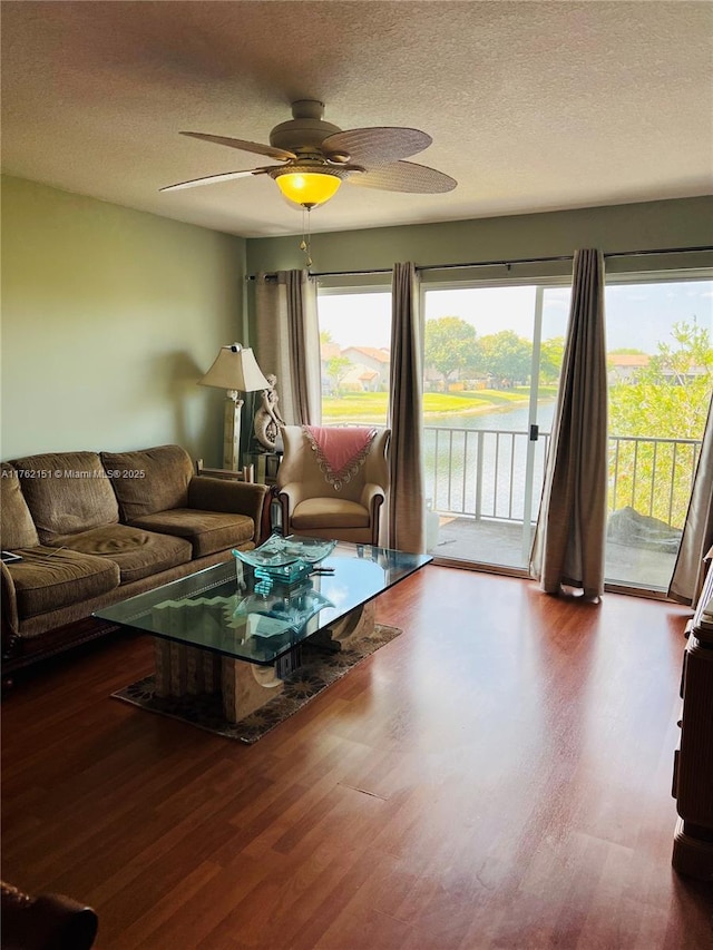 living room with a textured ceiling, wood finished floors, and a ceiling fan