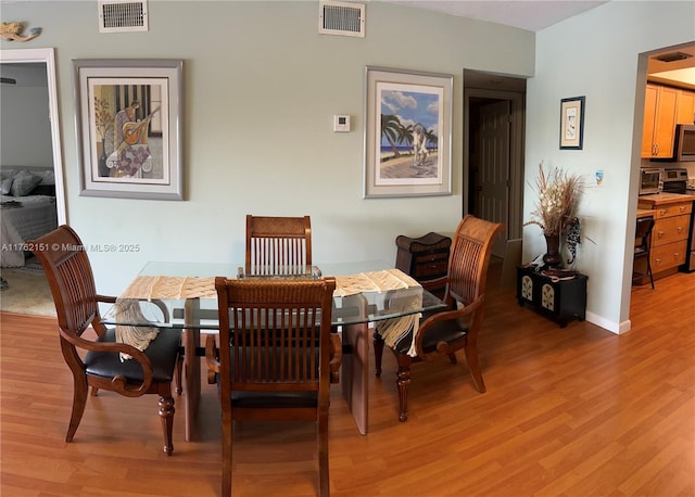 dining space with light wood-style flooring, a toaster, and visible vents