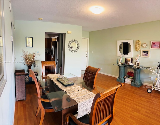 dining room with baseboards, a textured ceiling, and wood finished floors