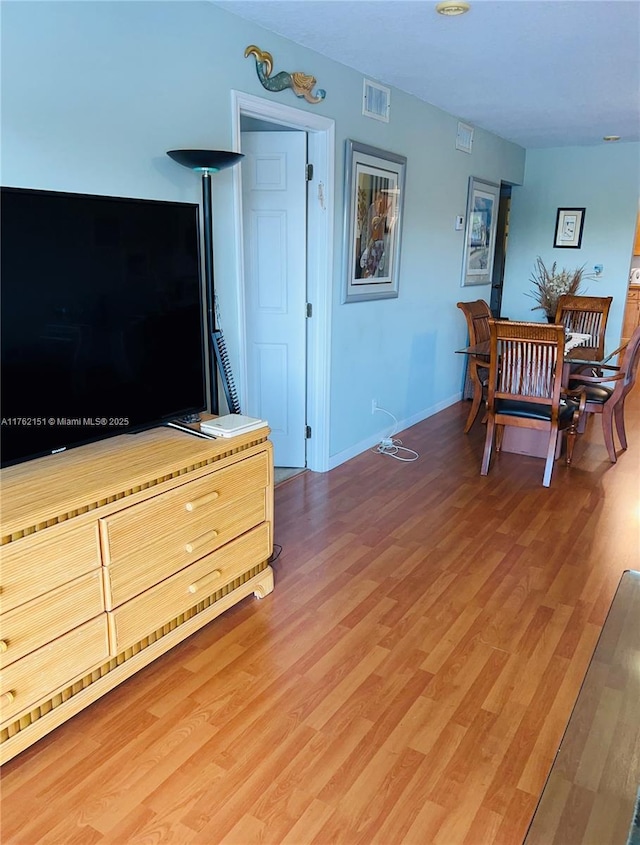 living area with visible vents, baseboards, and light wood finished floors