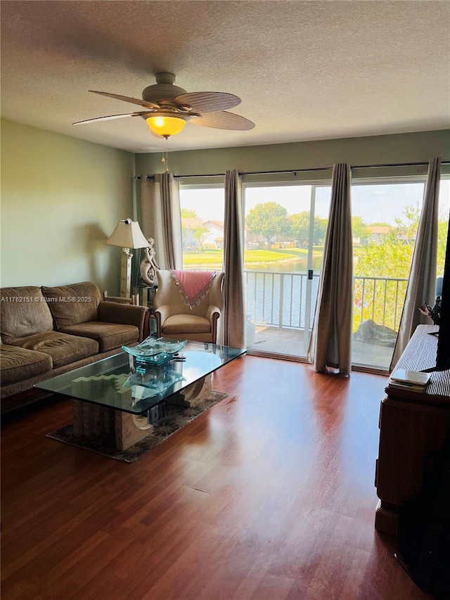 living room featuring ceiling fan, a textured ceiling, and wood finished floors