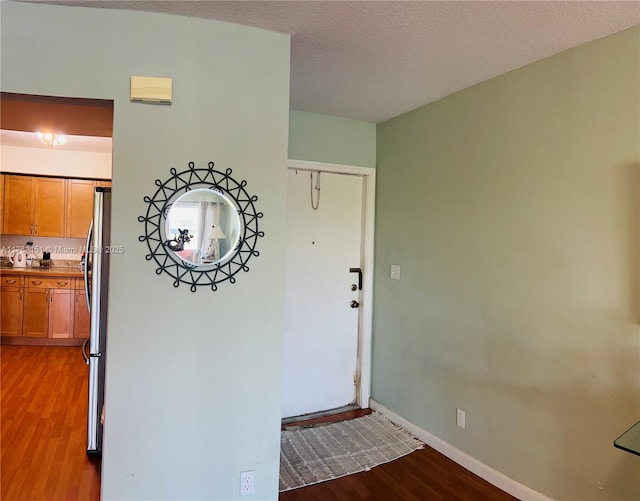 entrance foyer featuring a textured ceiling, baseboards, and wood finished floors