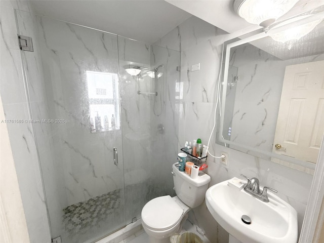 bathroom with a sink, a marble finish shower, toilet, and tile walls