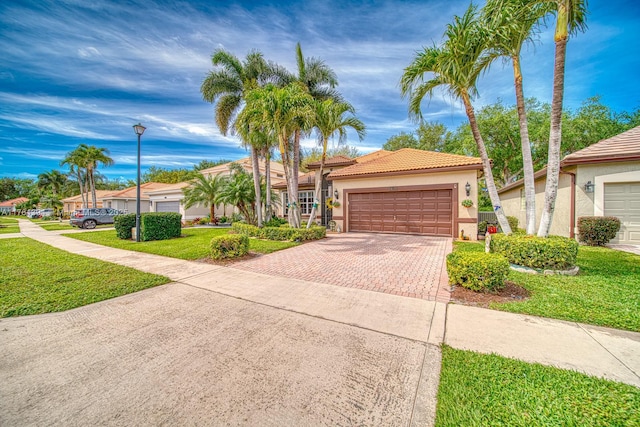 view of front of property featuring stucco siding, decorative driveway, an attached garage, a front yard, and a tiled roof