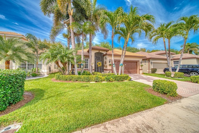 mediterranean / spanish-style home featuring stucco siding, driveway, a tile roof, a front yard, and a garage