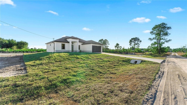 view of front facade with stucco siding, driveway, an attached garage, and a front yard