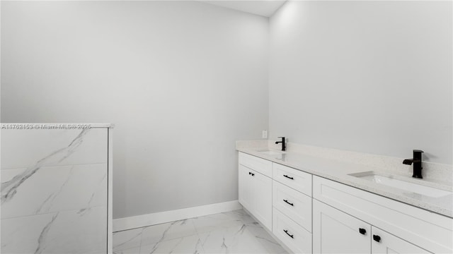 bathroom featuring a sink, baseboards, marble finish floor, and double vanity