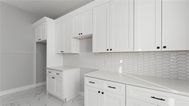 kitchen with backsplash, baseboards, light stone countertops, white cabinets, and marble finish floor