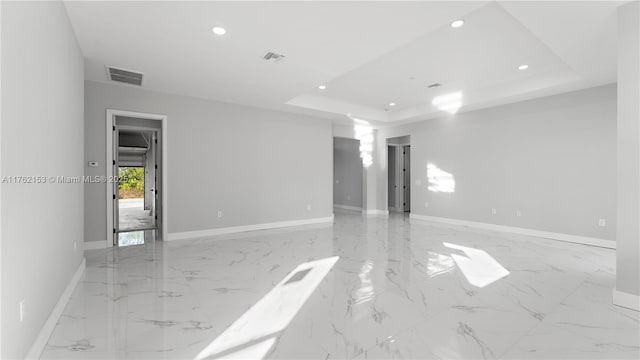 empty room featuring visible vents, baseboards, a tray ceiling, recessed lighting, and marble finish floor