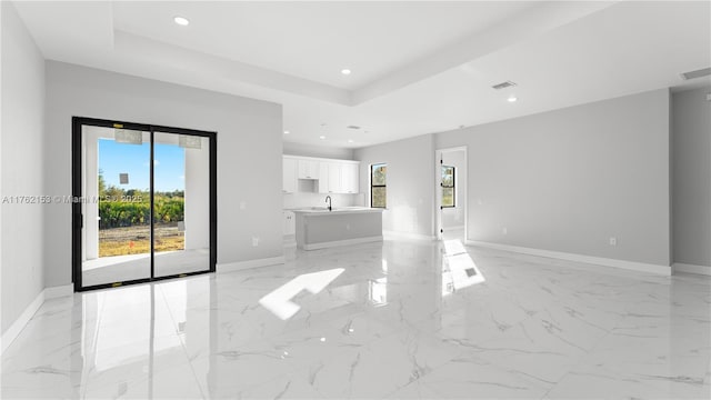 interior space featuring a raised ceiling, recessed lighting, baseboards, and a sink