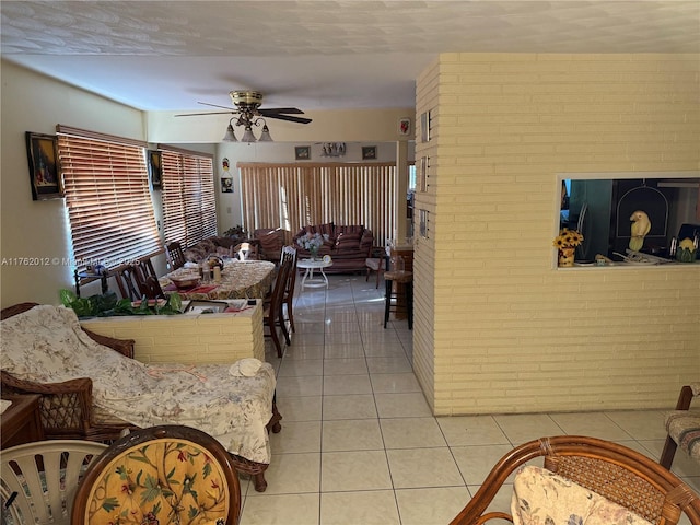 dining space featuring light tile patterned floors, brick wall, and a ceiling fan