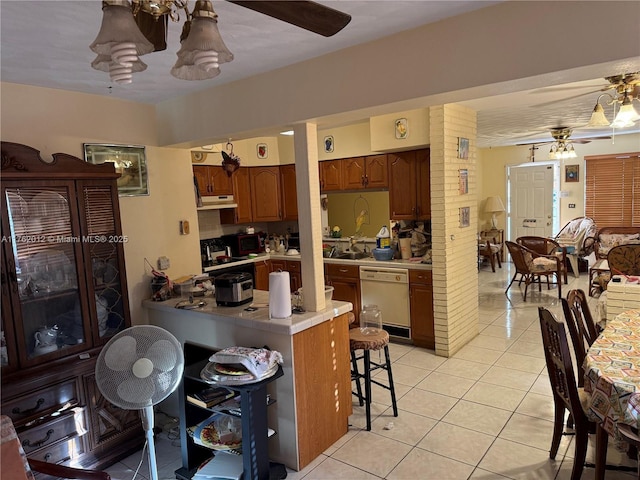 kitchen with dishwasher, a breakfast bar area, light countertops, light tile patterned flooring, and a ceiling fan