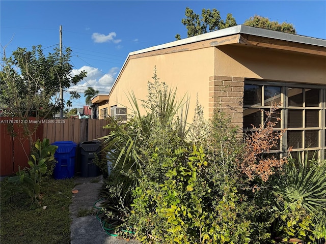 view of side of property featuring stucco siding and fence