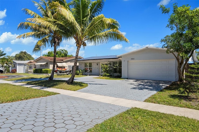 ranch-style house with decorative driveway, a garage, roof mounted solar panels, and stucco siding