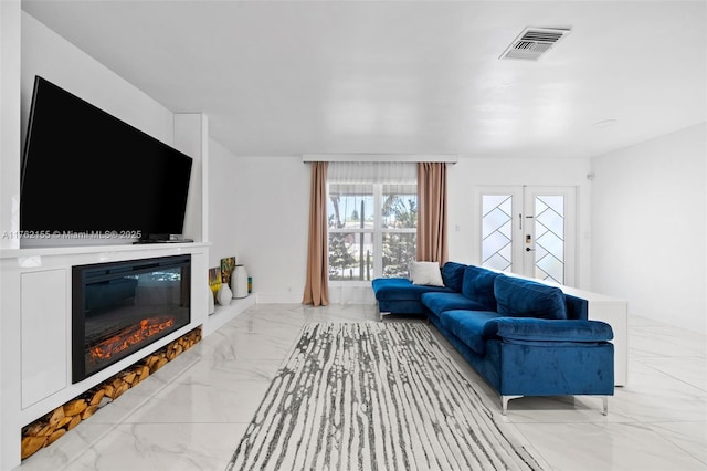 living room with visible vents, marble finish floor, a glass covered fireplace, and french doors