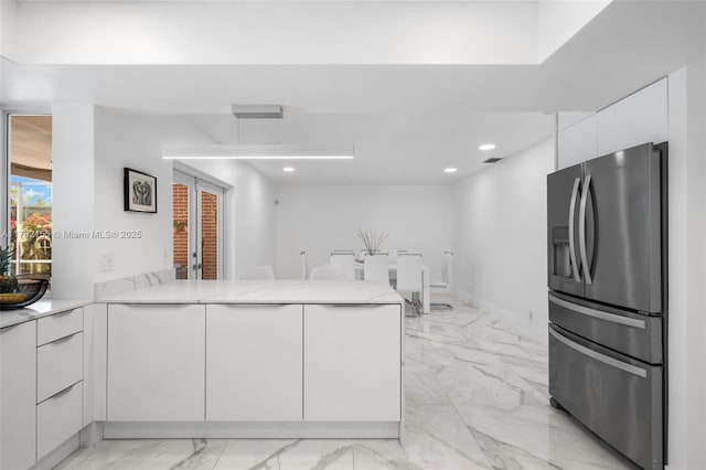 kitchen featuring a peninsula, white cabinets, stainless steel refrigerator with ice dispenser, marble finish floor, and modern cabinets