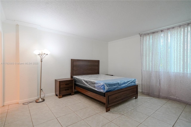 bedroom featuring a textured ceiling, light tile patterned floors, baseboards, and ornamental molding