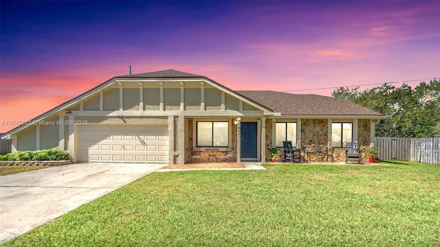 view of front of house with board and batten siding, fence, a lawn, a garage, and driveway