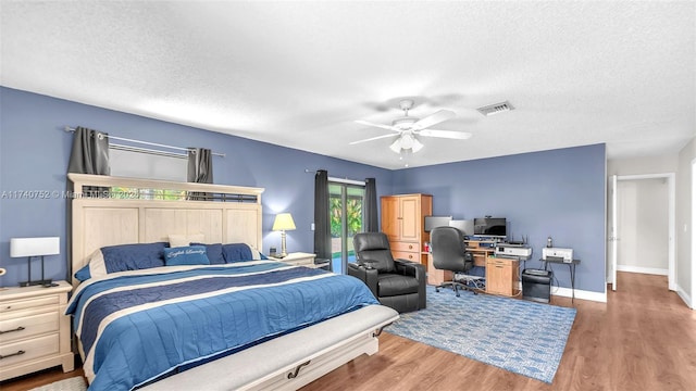 bedroom with visible vents, baseboards, a textured ceiling, and wood finished floors