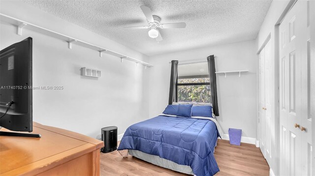 bedroom featuring baseboards, a textured ceiling, ceiling fan, and wood finished floors