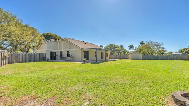 view of yard with an outbuilding, a shed, a patio area, and a fenced backyard