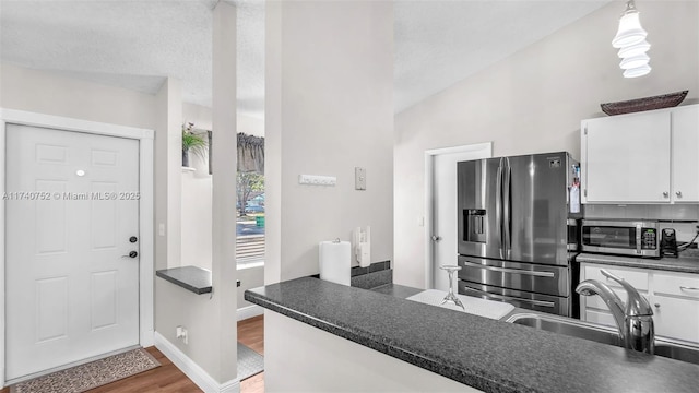 kitchen featuring white cabinetry, dark countertops, wood finished floors, and stainless steel refrigerator with ice dispenser