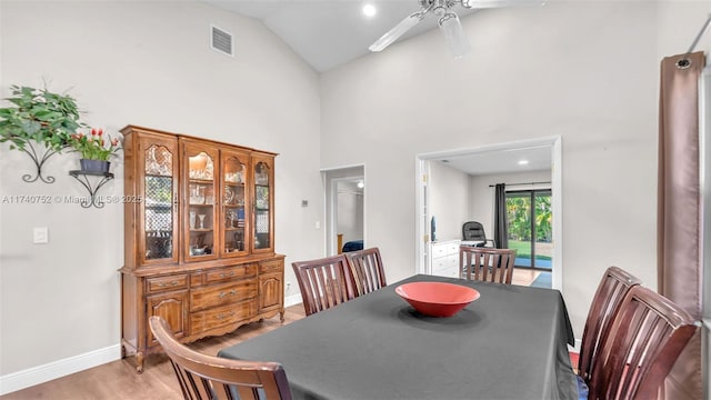 dining area featuring visible vents, baseboards, light wood-style flooring, high vaulted ceiling, and a ceiling fan