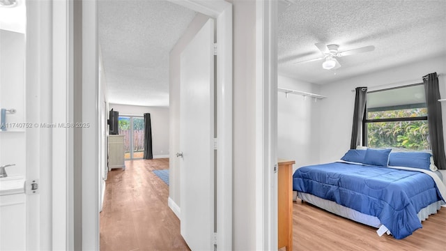 bedroom with baseboards, a textured ceiling, wood finished floors, and a ceiling fan