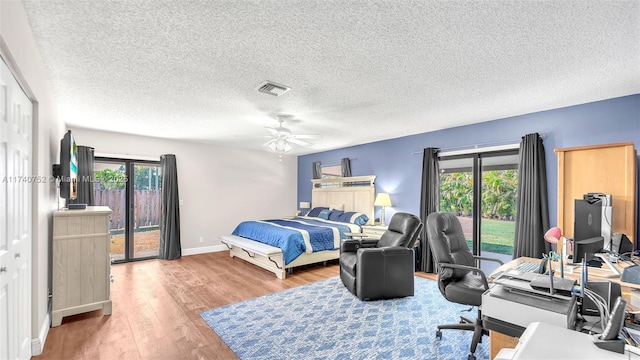 bedroom with a ceiling fan, access to exterior, wood finished floors, and visible vents