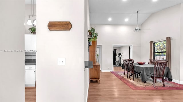 dining room with wood finished floors, baseboards, a towering ceiling, and ceiling fan