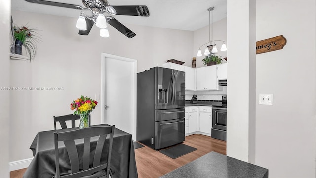 kitchen with dark countertops, fridge with ice dispenser, decorative backsplash, electric range, and white cabinets