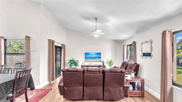 living room with visible vents, a textured ceiling, light wood-style floors, and lofted ceiling