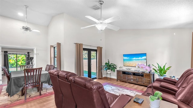 living room featuring a ceiling fan, wood finished floors, visible vents, high vaulted ceiling, and french doors