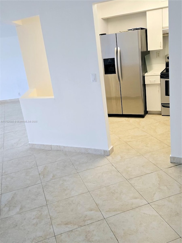 kitchen featuring appliances with stainless steel finishes, white cabinets, light countertops, light tile patterned floors, and baseboards