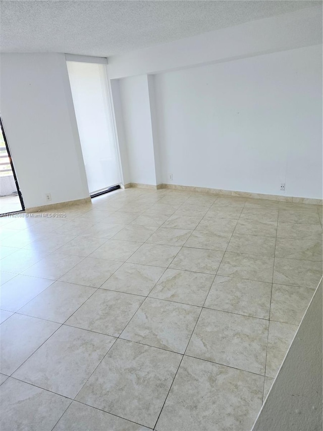 3300 NE 191st St Unit 609, Aventura, FL 33180 - empty room featuring light tile patterned floors, a textured ceiling, baseboards, and a baseboard radiator