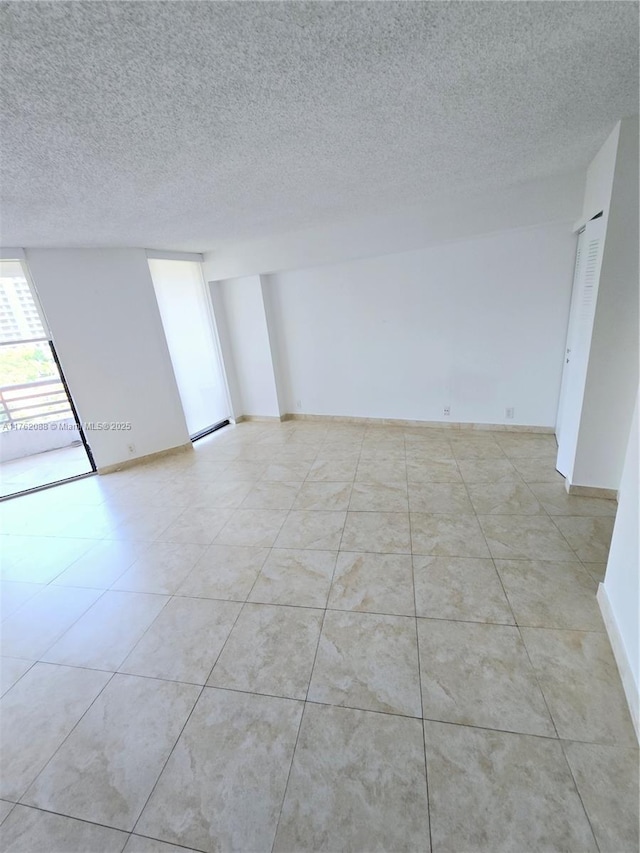3300 NE 191st St Unit 609, Aventura, FL 33180 - spare room with light tile patterned floors, a textured ceiling, and baseboards