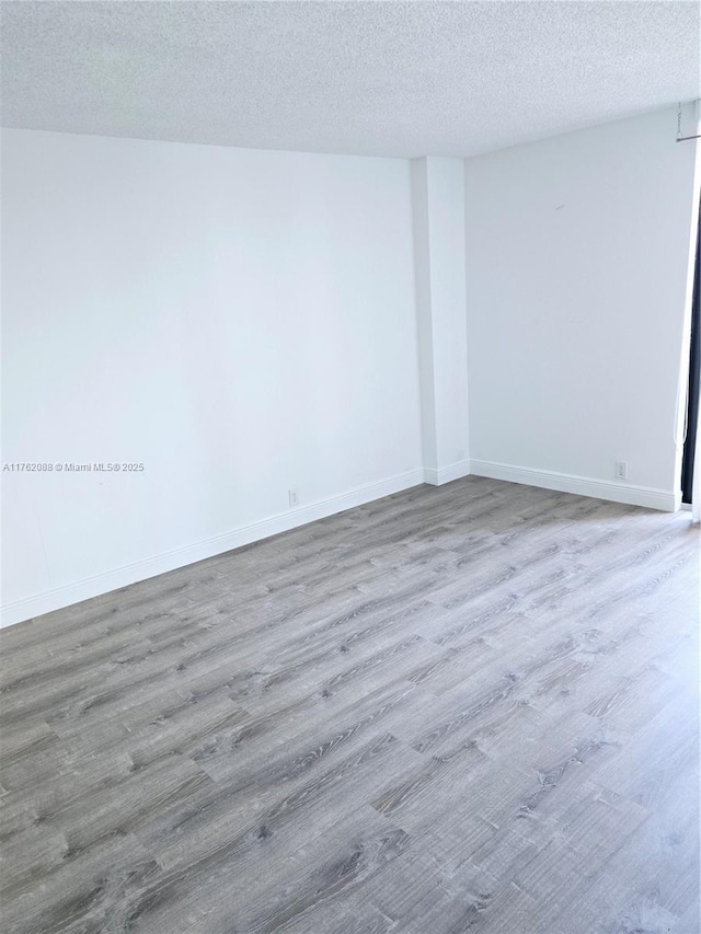 3300 NE 191st St Unit 609, Aventura, FL 33180 - unfurnished room with baseboards, a textured ceiling, and wood finished floors
