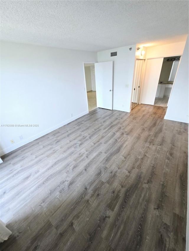 3300 NE 191st St Unit 609, Aventura, FL 33180 - unfurnished living room with visible vents, baseboards, a textured ceiling, and wood finished floors