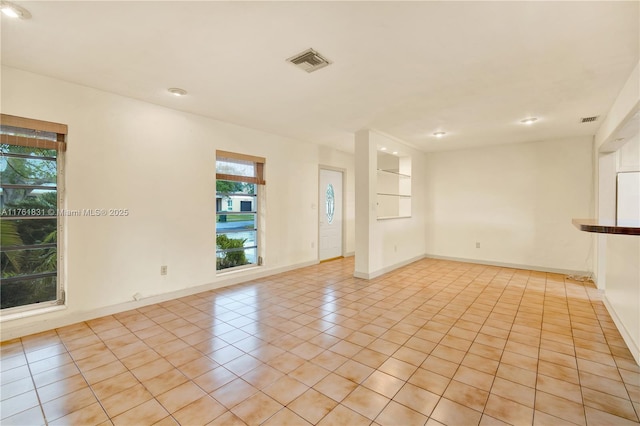 spare room with light tile patterned flooring, visible vents, and baseboards