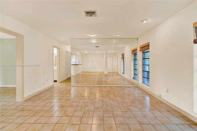 empty room featuring light tile patterned flooring, visible vents, plenty of natural light, and baseboards