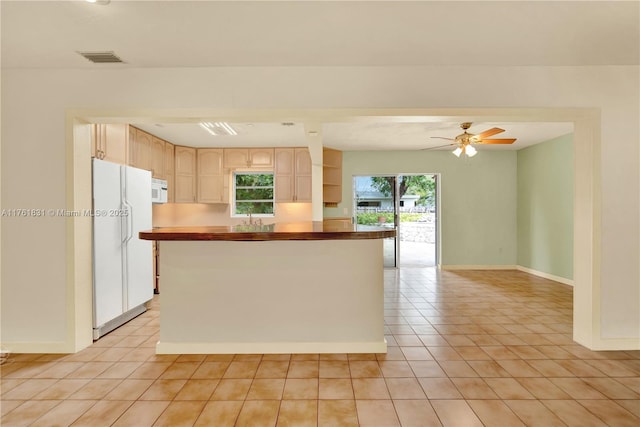 kitchen with white appliances, light tile patterned flooring, baseboards, and a wealth of natural light