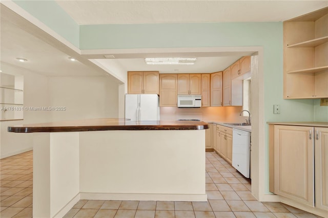 kitchen with a kitchen island, light brown cabinetry, light tile patterned floors, white appliances, and a sink