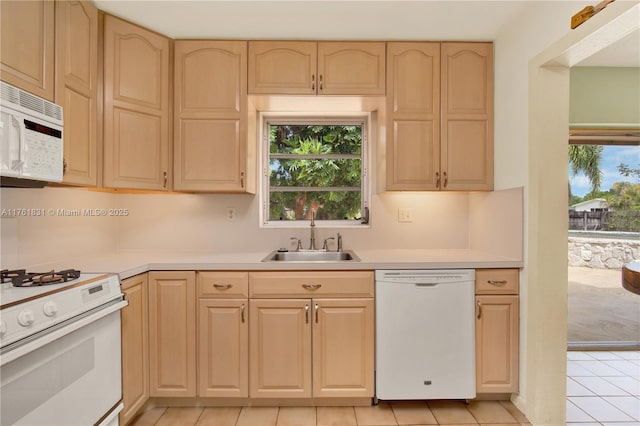 kitchen featuring white appliances, light brown cabinets, and a sink