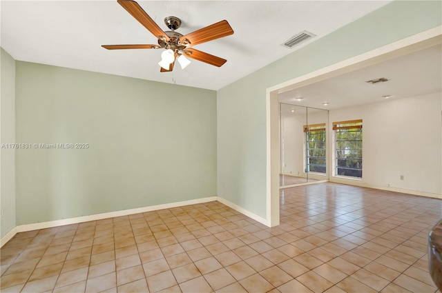 unfurnished room featuring light tile patterned flooring, visible vents, a ceiling fan, and baseboards