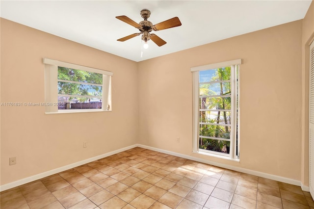 empty room with light tile patterned floors, ceiling fan, and baseboards